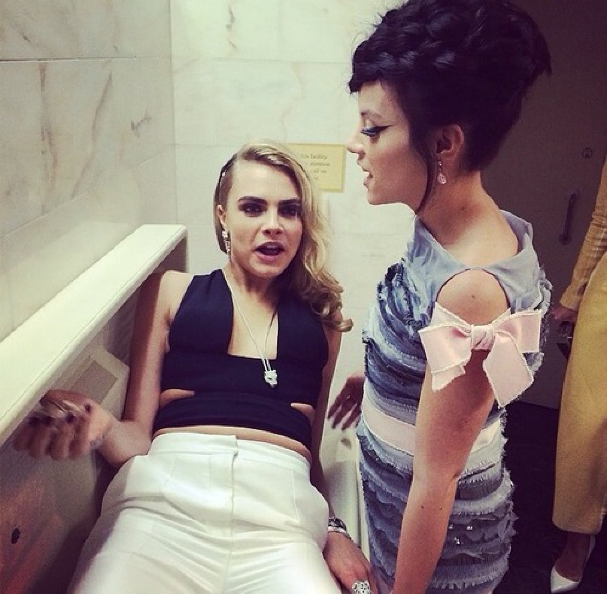 Cara Delevingne (vľavo) si urobila pohodlie na záchode. Vpravo stojí Lily Allen