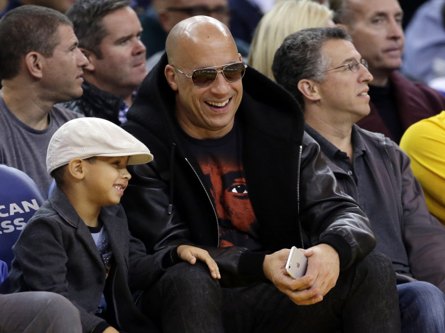 Herec Vin Diesel sleduje basketbalový zápas so svojím synom Vincentom.