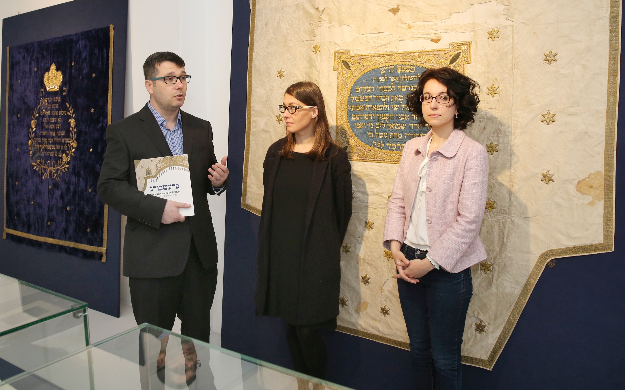 Kurátorka výstavy Jana Švantnerová, za ňou textília zo zbúranej synagógy na Zámockej ulici v  Bratislave, 1863/1864.