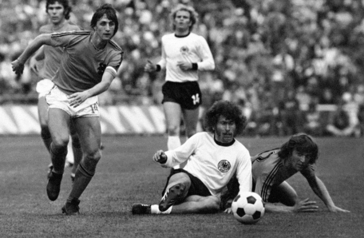 Johan Cruyff (vľavo) a jeho dres s dvomi pásikmi. Na zemi bojuje o loptu Nemec Paul Breitner. Momentka je z finálového zápasu.