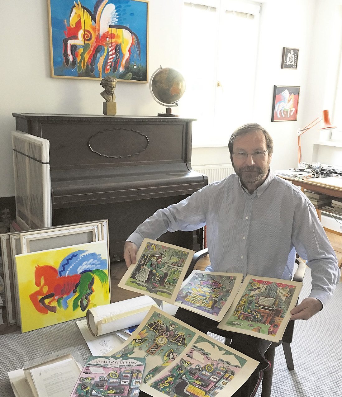 Maliar, ilustrátor a grafik Martin Kellenberger v ateliéri s knihou Čárymáryfučpunč a ilustráciami, ktoré čakali na zverejnenie takmer 30 rokov.