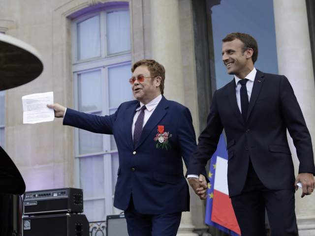 Francúzsky prezident Emmanuel Macron (vpravo) drží za ruku speváka - Sira Eltona Johna pred príhovorom, ktorý dvojica absolvovala v Elyzejskom paláci. 