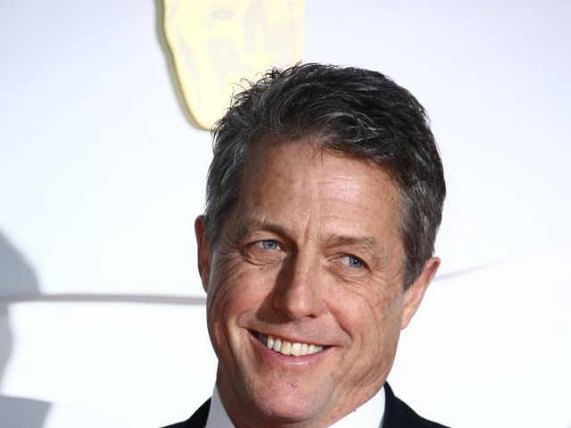 Herec Hugh Grant pózuje fotografom. 