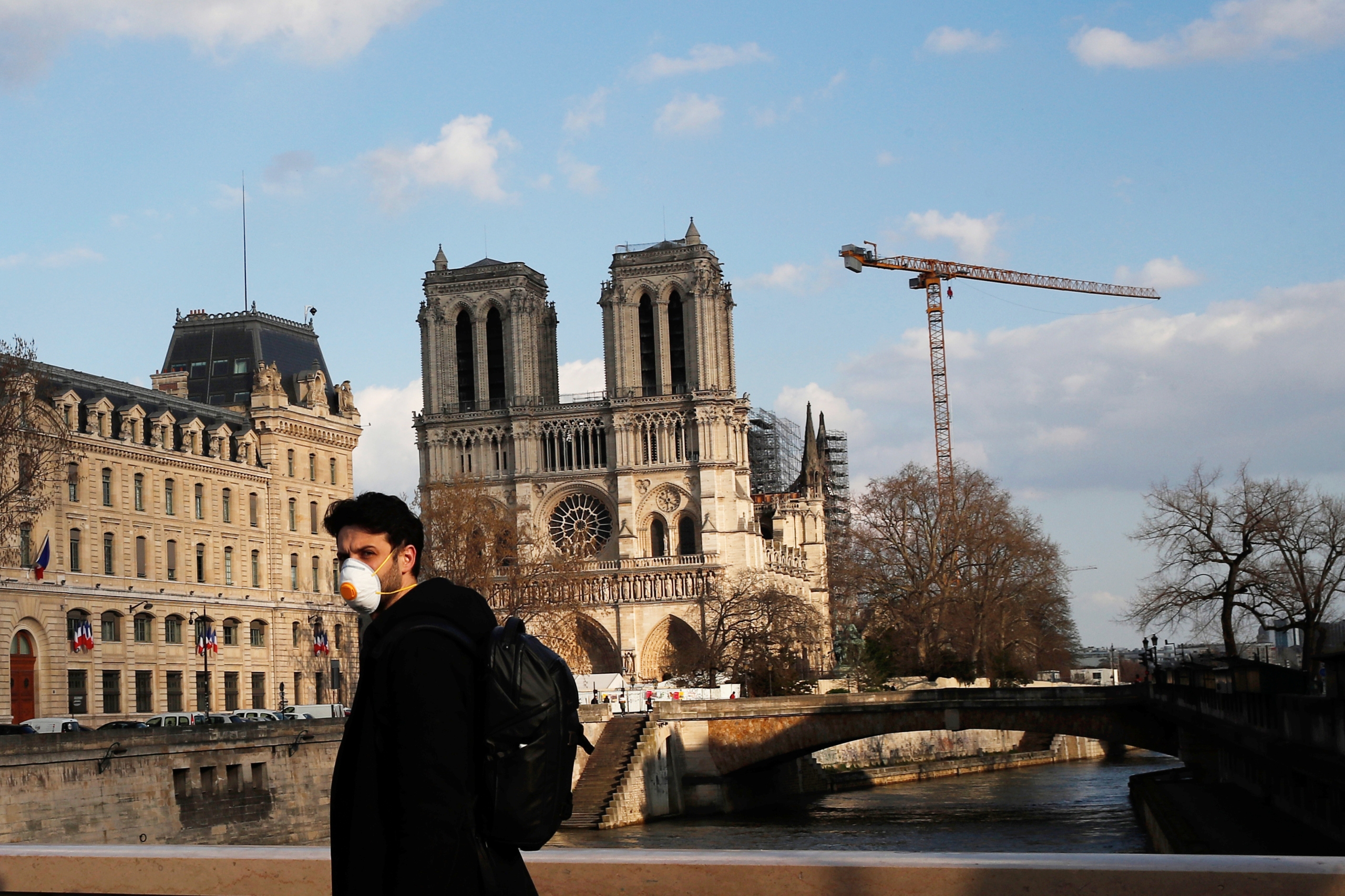 Parížan s rúškom prechádza popred Notre-Dame, ktorá po strašnom požiari musí prejsť rozsiahlou rekonštrukciou.