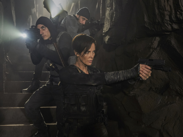 Herečka Charlize Theron (v popredí) na zábere z filmu The Old Guard. Za ňou herci Luca Marinelli (v strede) a Matthias Schoenaerts.
