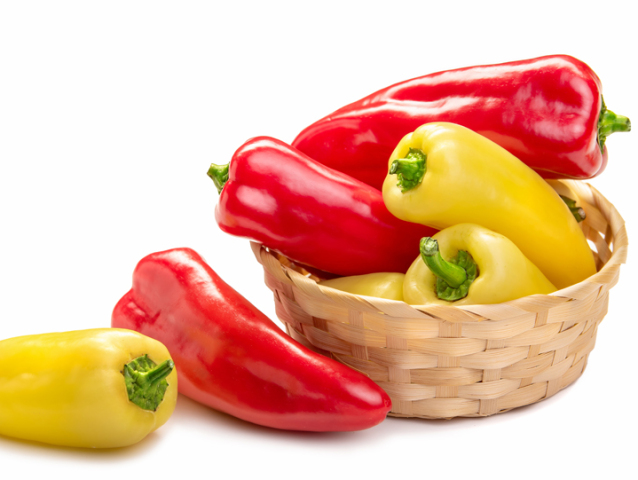 red and yellow pointed paprika in a basket. Isolate on white background 