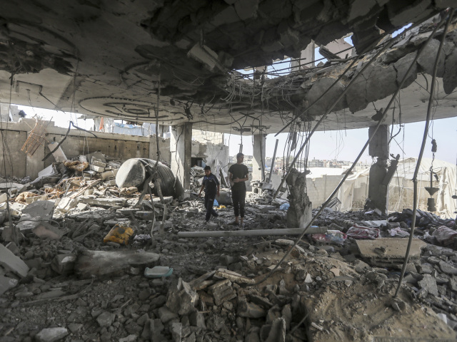 Palestínčania stoja v troskách rodinného domu po nočnom izraelskom údere, pri ktorom zahynuli najmenej dvaja dospelí a päť chlapcov a dievčat mladších ako 16 rokov v Rafahu v južnom pásme Gazy v piatok 3. mája 2024.