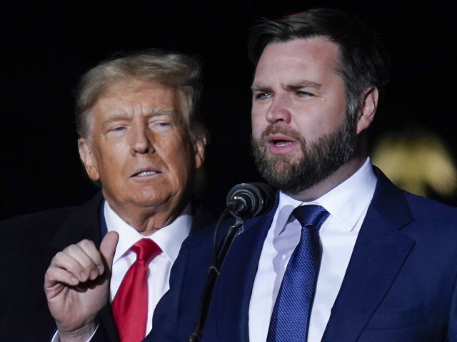 Senátor v Ohiu J.D. Vance ešte ako kandidát na post, ktorý získal, hovorí s exprezidentom Donaldom Trumpom v pozadí na predvolebnom zhromaždení na letisku v Daytone 7. novembra 2022.