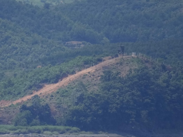 V pozadí severokórejská strážna veža spolu s plotom a ostnatým drôtom pri juhokórejskom meste Padžu na hraniciach so Severnou Kóreou