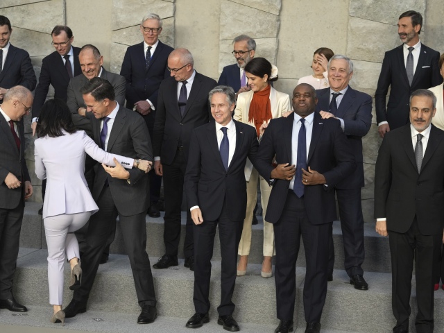 Generálny tajomník NATO Mark Rutt (vpredu vľavo), pomáha nemeckej ministerke zahraničných vecí Annalene Baerbockovej vystúpiť na pódium počas skupinovej fotografie na stretnutí ministrov zahraničných vecí členských krajín NATO v centrále NATO v Bruseli v stredu 4. decembra 2024.