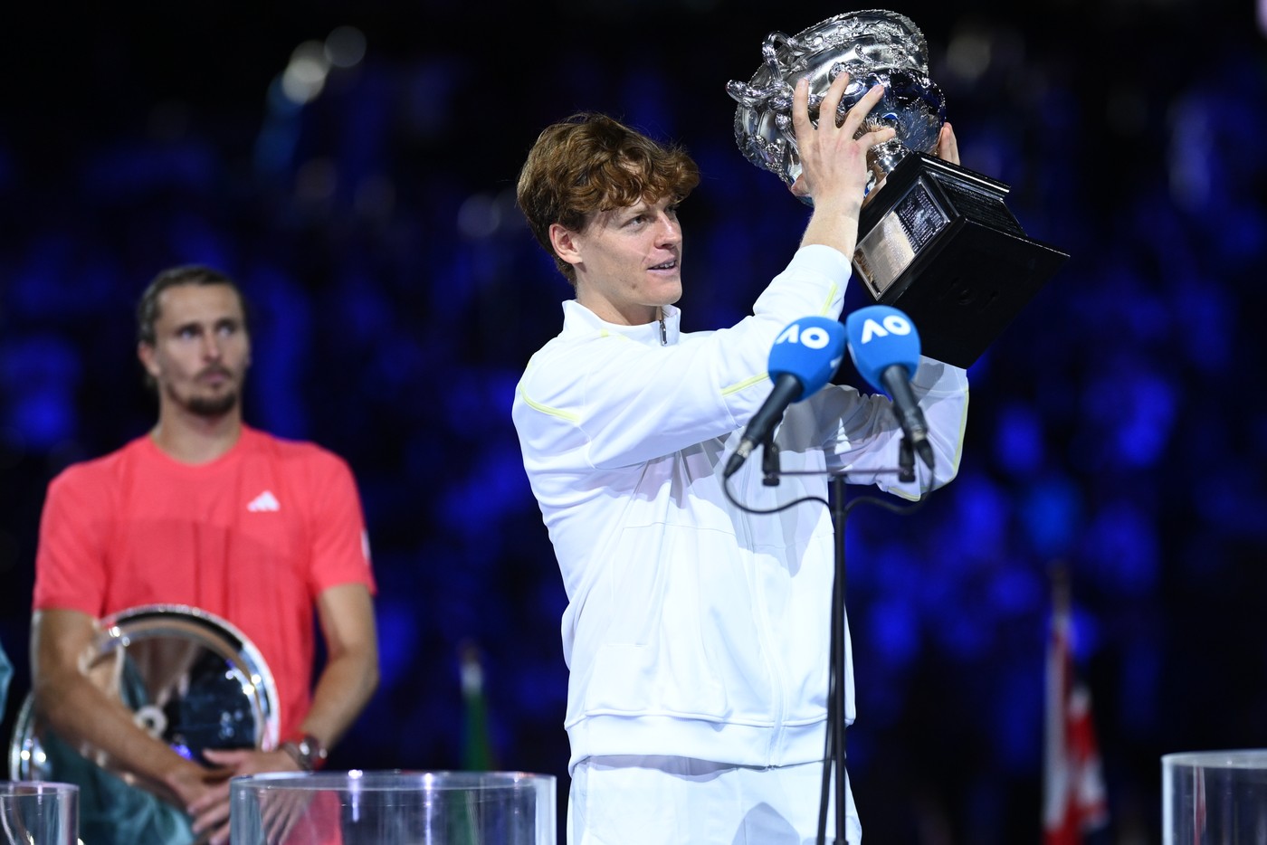 Jannik Sinner s trofejou, v pozadí sklamaný Alexander Zverev.