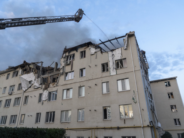 Hasič hasí z vysokozdvižného vozíka obytnú budovu, ktorú zasiahol raketový útok ruskej armády na obytnú budovu v ukrajinskom meste Charkov v pondelok 18. augusta 2025. FOTO TASR/AP