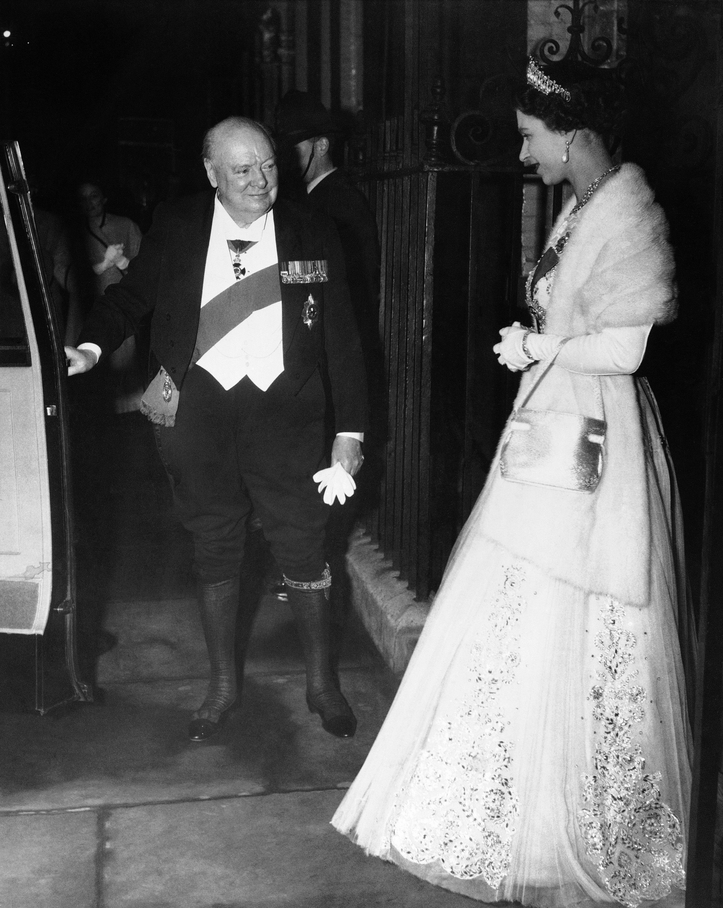 Džentlmen Winston Churchill otvára dvere auta britskej kráľovnej Alžbete II. (snímka z Londýna je z apríla 1955).