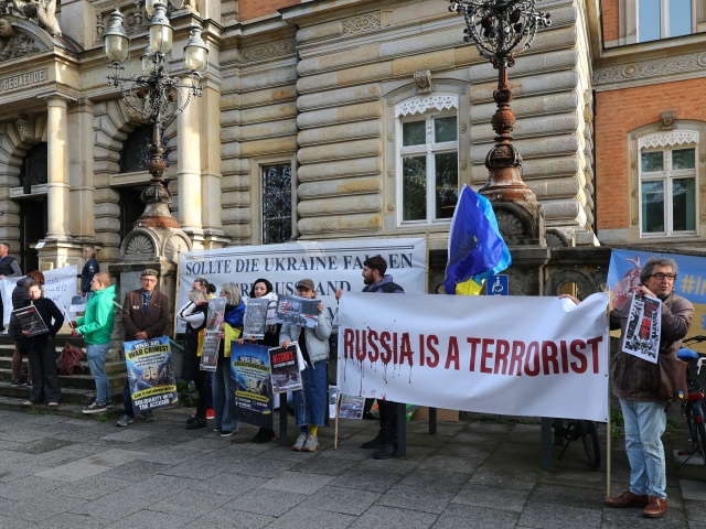 Ukrajinskí podporovatelia čakajú s transparentmi pred budovou Vyššieho krajinského súdu na začiatok procesu s Ukrajincom Serhijom Kuznecovom v kauze sabotáže plynovodov Nord Stream v Hamburgu 14. októbra 2026.
