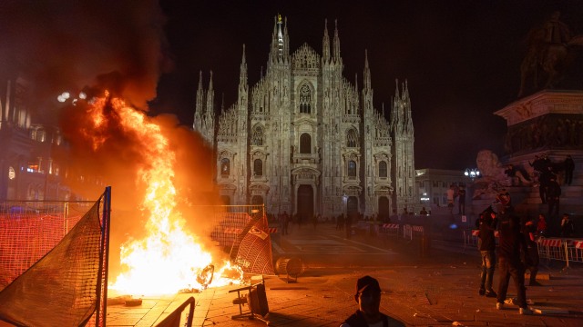 Po zrážkach medzi políciou a protestujúcimi z hnutia „Italia in Piazza“ pred milánskou katedrálou v talianskom Miláne horí oheň, sobota 17. októbra 2026.